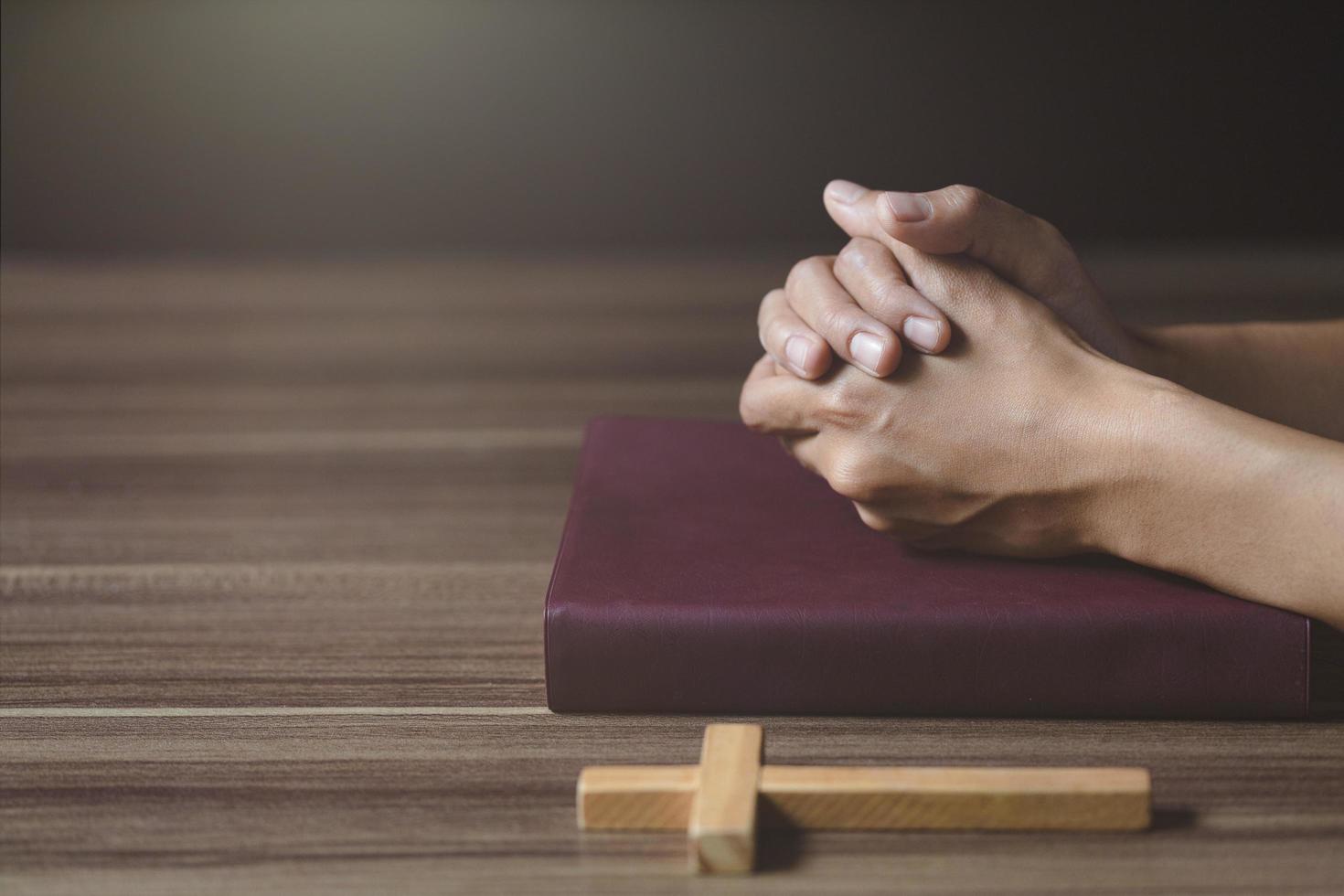 mains de femmes priant Dieu avec la bible. croire au bien. main dans la main en prière sur une table en bois. prière de crise de la vie chrétienne à dieu. photo