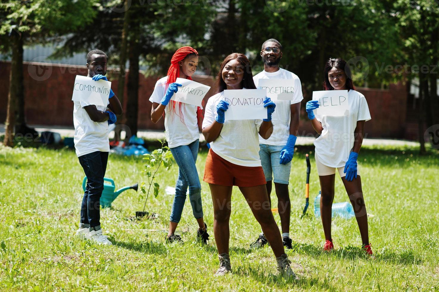 un groupe de volontaires africains heureux tient un tableau blanc avec un signe de don dans le parc. concept de volontariat, de charité, de personnes et d'écologie en afrique. photo
