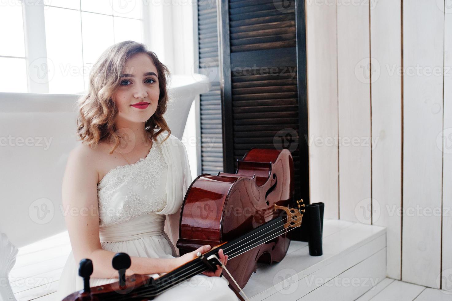 jolie jeune musicienne gilrl en robe blanche avec contrebasse. photo