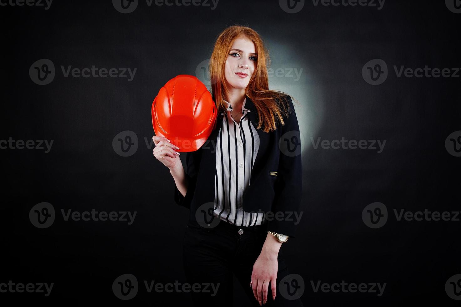 femme ingénieur en casque de protection orange sur fond noir de studio. photo