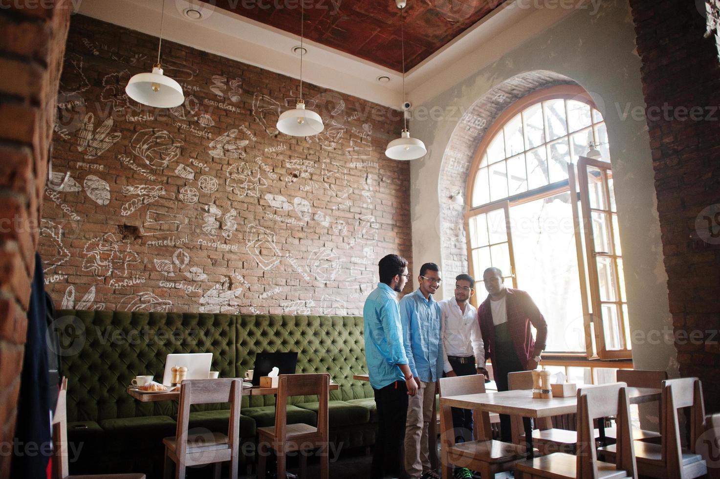 groupe de quatre hommes sud-asiatiques posés lors d'une réunion d'affaires au café. indiens ayant la conversation. photo