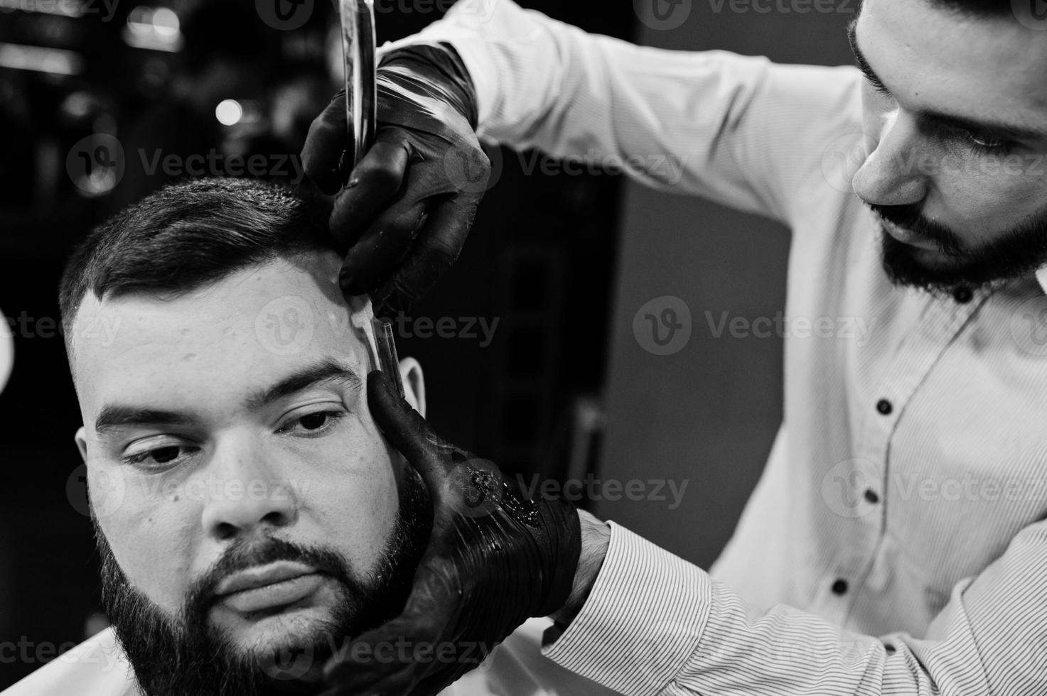 bel homme barbu au salon de coiffure, coiffeur au travail. photo