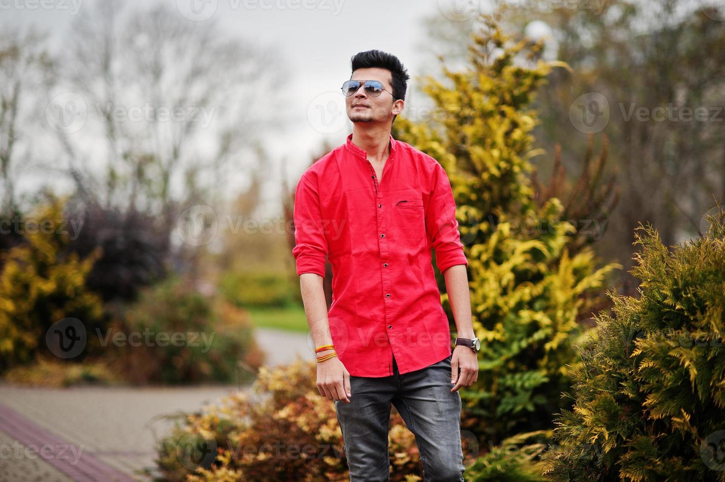 homme indien en chemise rouge et lunettes de soleil posées à l'extérieur. photo