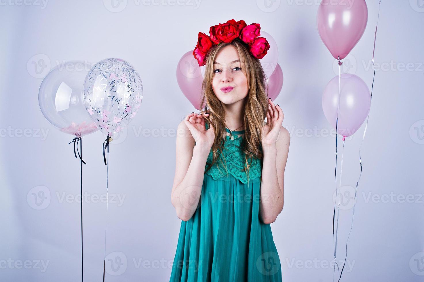 fille heureuse en robe turquoise verte et couronne avec des ballons colorés isolés sur blanc. célébrer le thème de l'anniversaire. photo