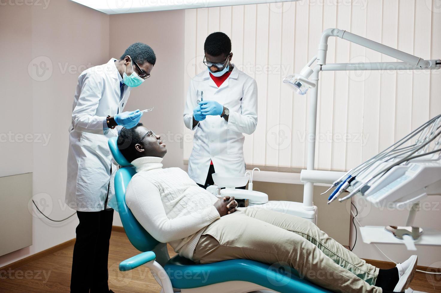 patient afro-américain dans un fauteuil dentaire. cabinet de dentiste et concept de cabinet médical. dentiste professionnel aidant son patient à la dentisterie médicale. anesthésique par injection. photo