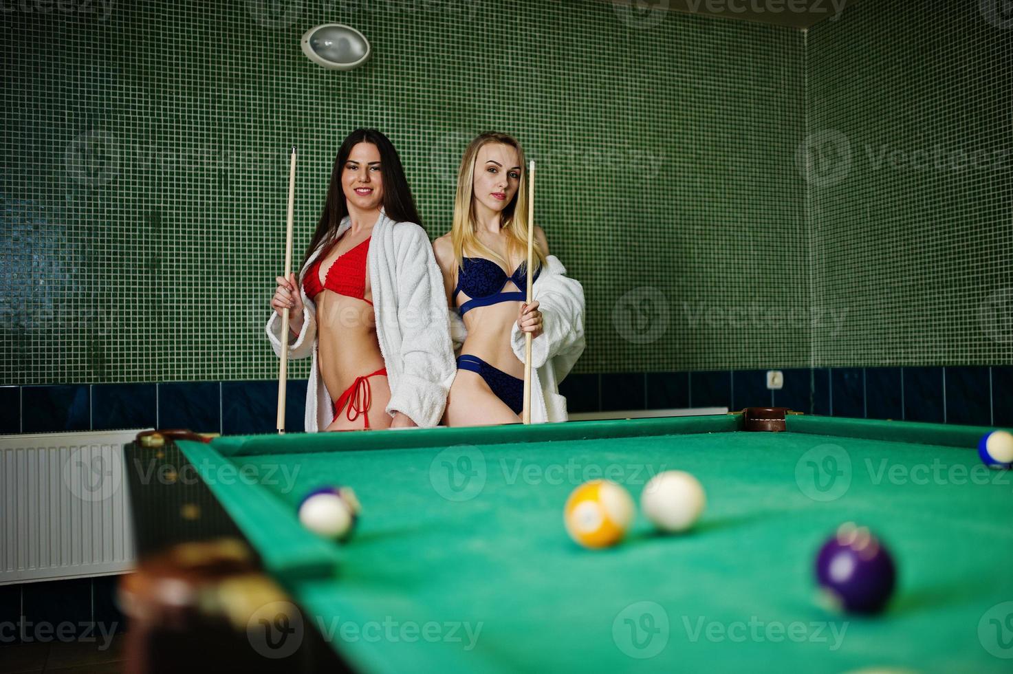 deux filles sexy en peignoir blanc et maillot de bain jouent au billard. photo