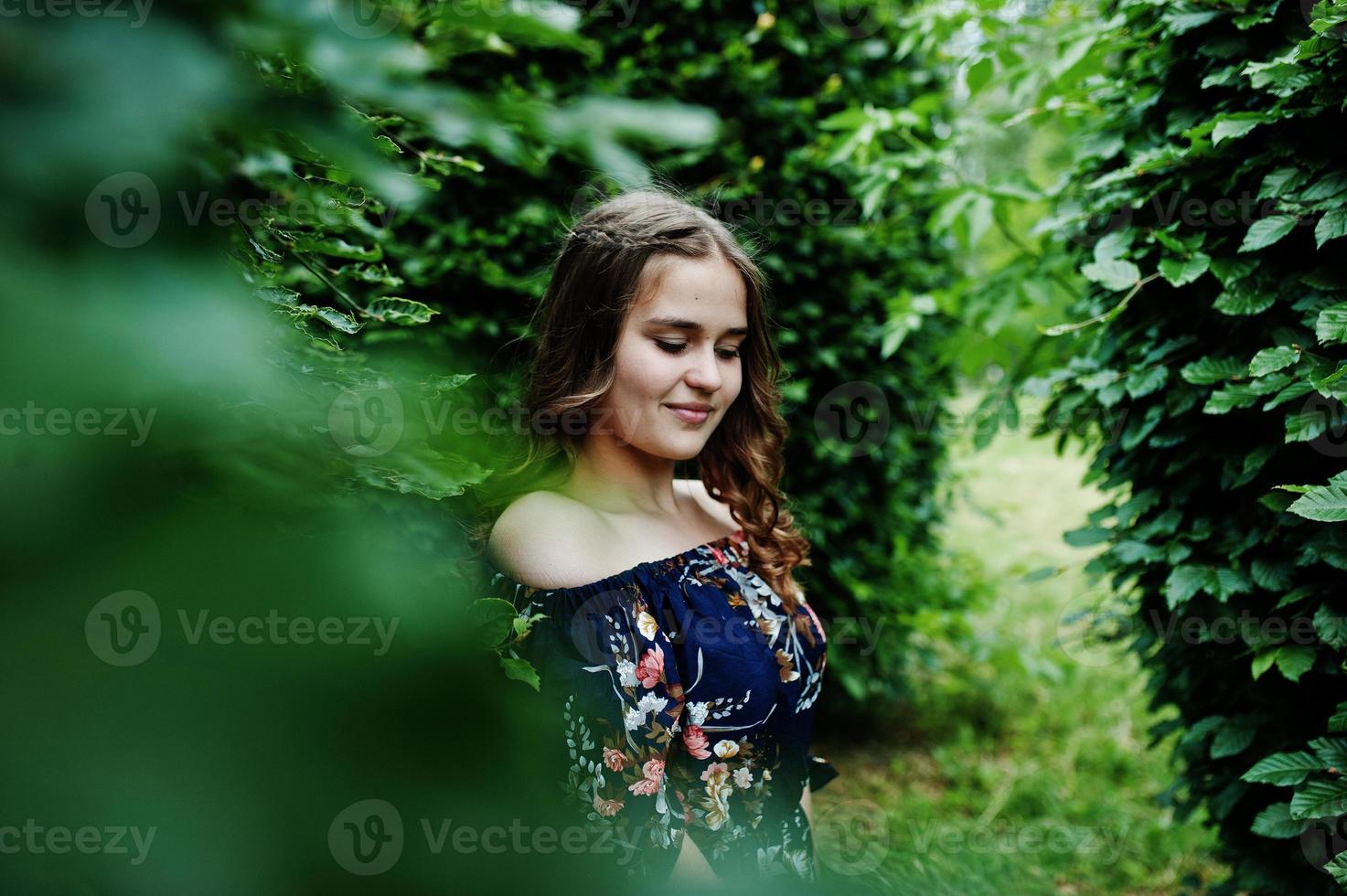 portrait d'une fabuleuse jeune fille en jolie robe avec une coiffure bouclée élégante posant dans la forêt ou le parc. photo