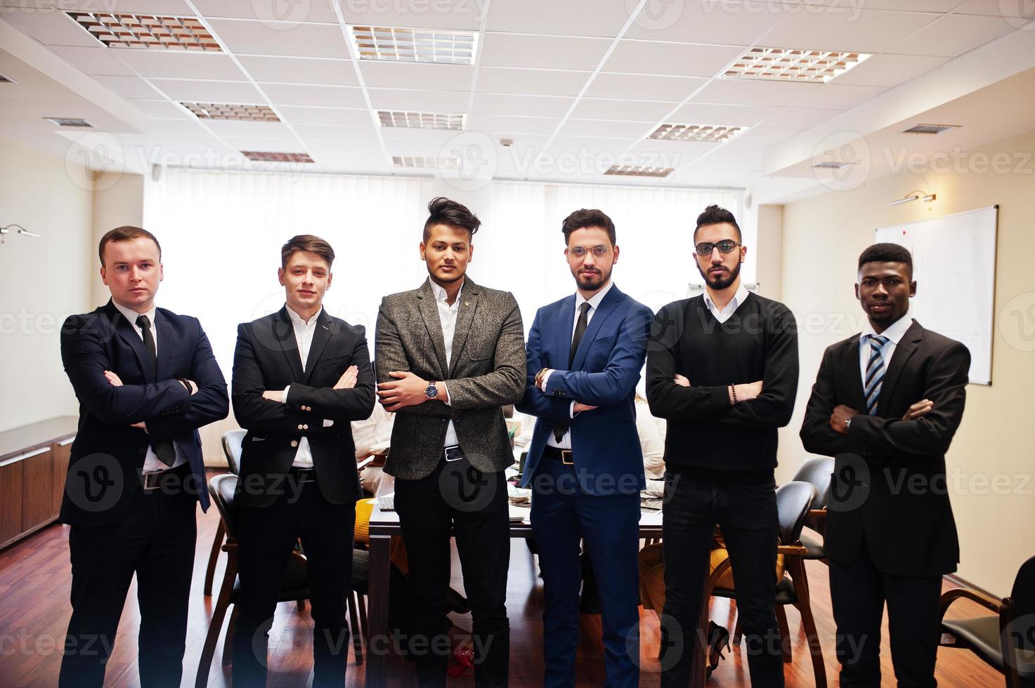 six hommes d'affaires multiraciaux debout au bureau avec les bras croisés. groupe diversifié d'employés masculins en tenue de soirée. photo