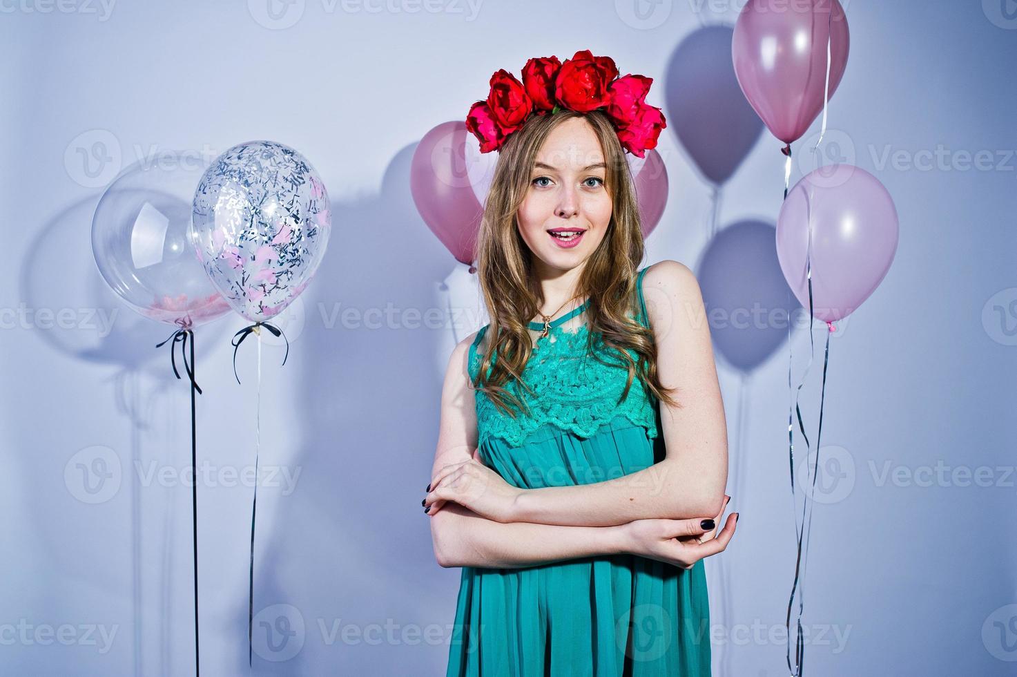 fille heureuse en robe turquoise verte et couronne avec des ballons colorés isolés sur blanc. célébrer le thème de l'anniversaire. photo