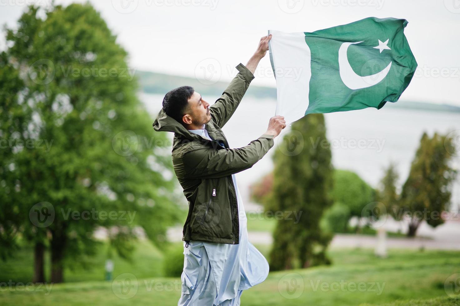vêtements traditionnels portrait masculin pakistanais indien tenir le drapeau du pakistan. photo