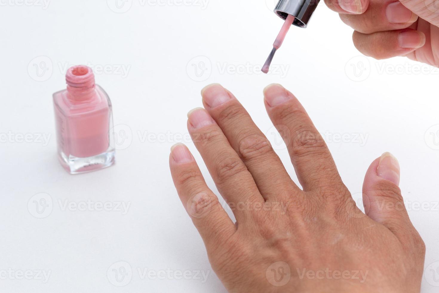 mains de femme peignant des ongles sur fond blanc photo