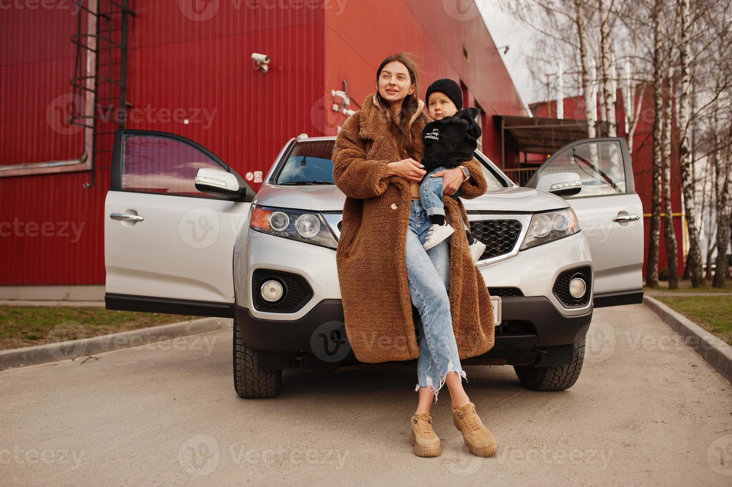 jeune mère et enfant se tiennent près de leur voiture suv. concept de conduite de sécurité. photo