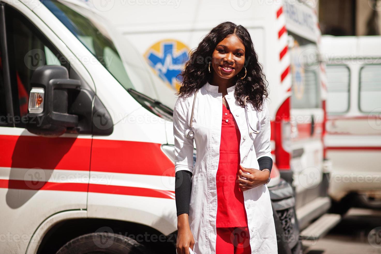 paramédic femme afro-américaine debout devant la voiture d'ambulance. photo