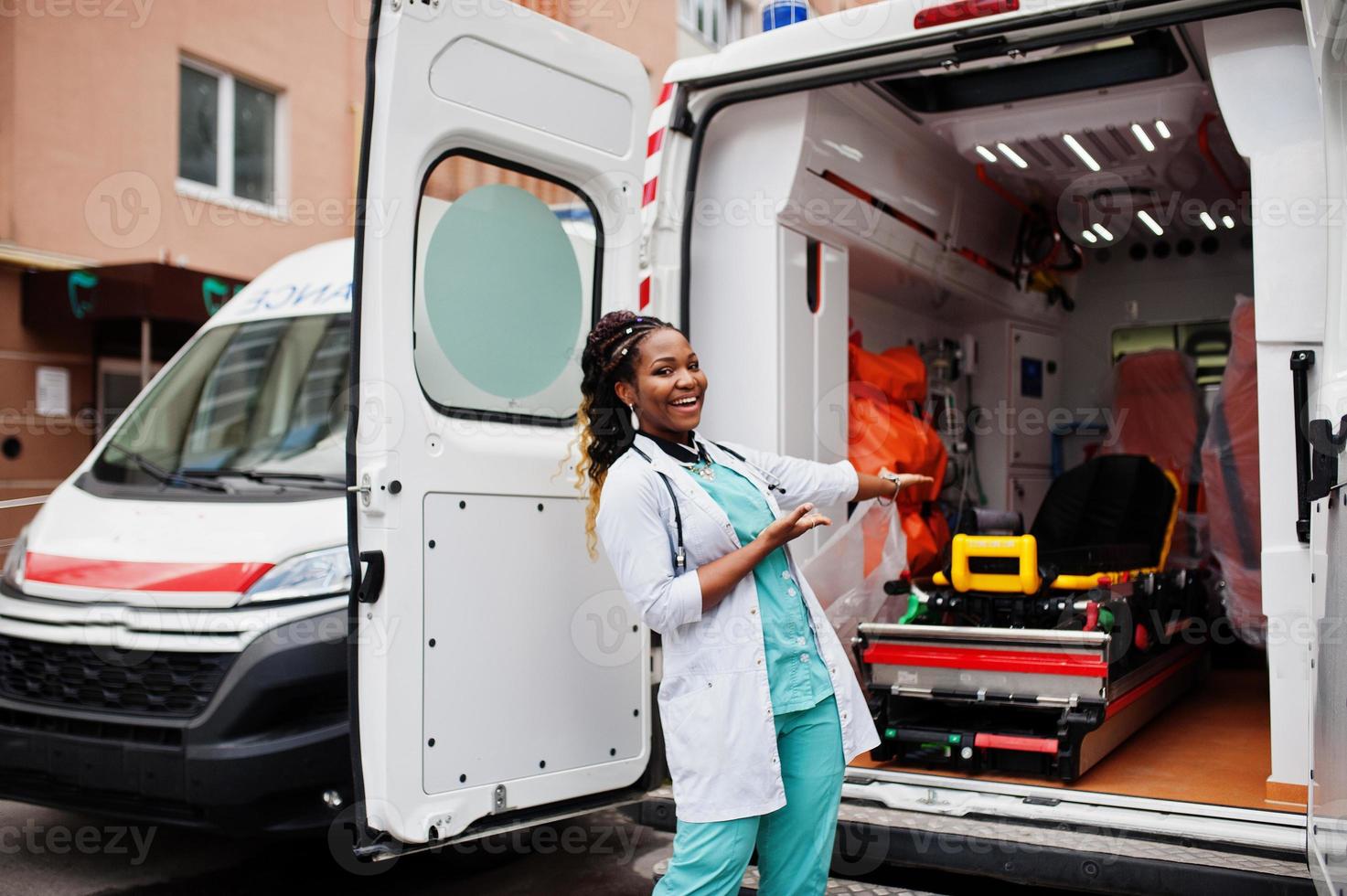 paramédic femme afro-américaine debout devant la voiture d'ambulance. photo