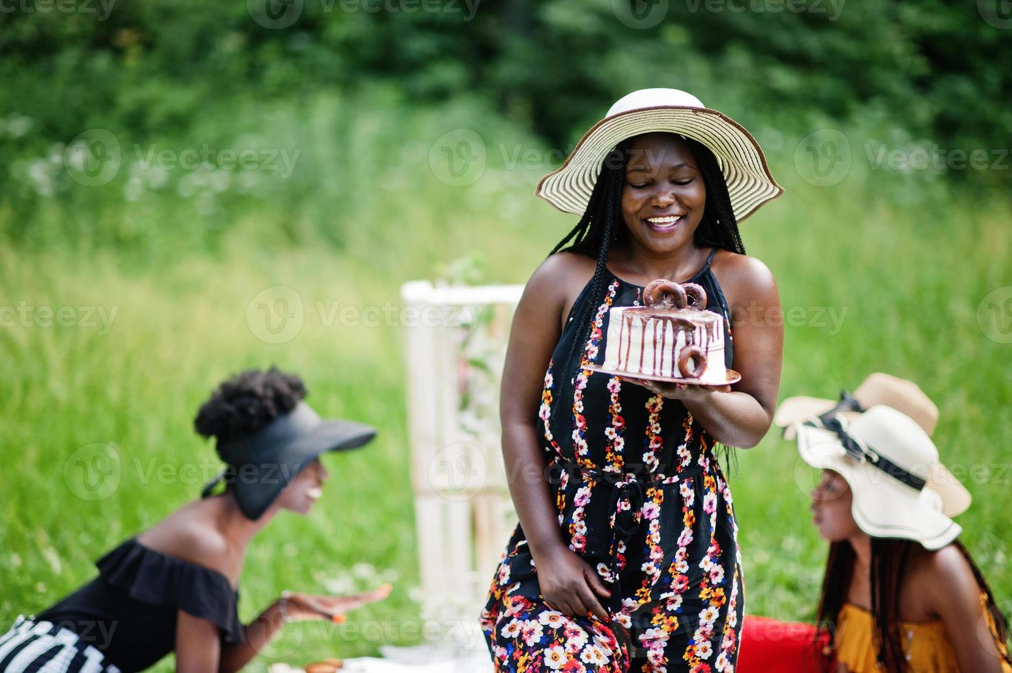 groupe de filles afro-américaines célébrant la fête d'anniversaire et tenant un gâteau en plein air avec un décor. photo