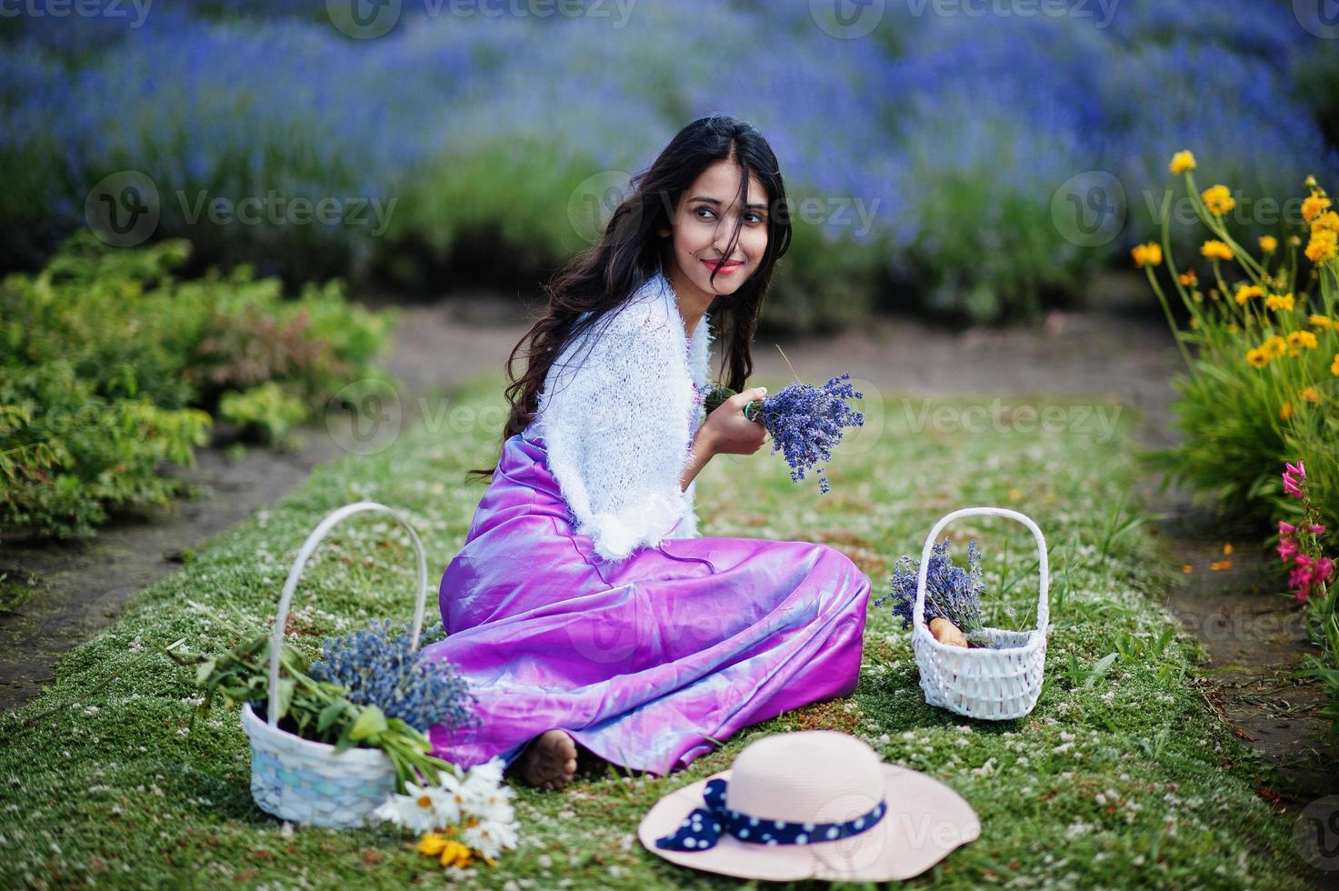 belle fille indienne porte une robe traditionnelle indienne saree dans un champ de lavande violette. photo