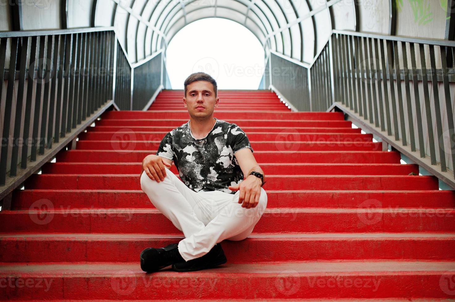 portrait de style de vie de bel homme posant dans les escaliers rouges du tonnel de la ville. photo