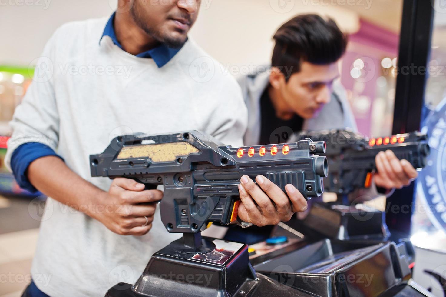 deux mecs asiatiques s'affrontent sur une machine d'arcade de jeu de simulateur de tir. photo