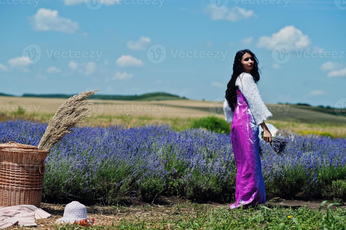 belle fille indienne porte une robe traditionnelle indienne saree dans un champ de lavande violette avec panier. photo