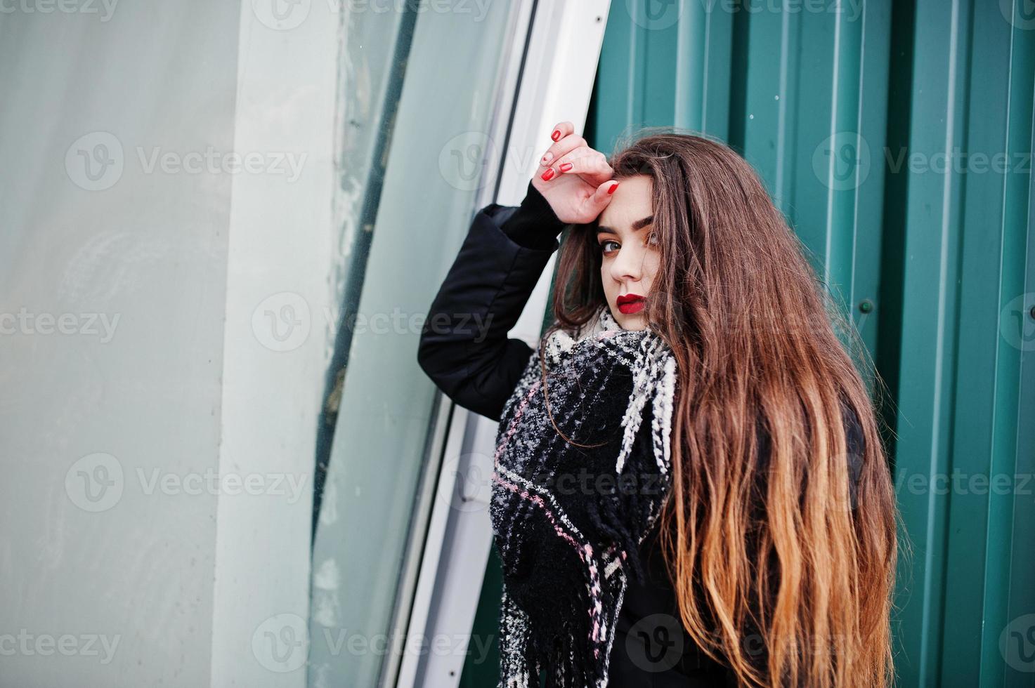 brune élégante fille décontractée en écharpe contre un mur métallique vert. photo