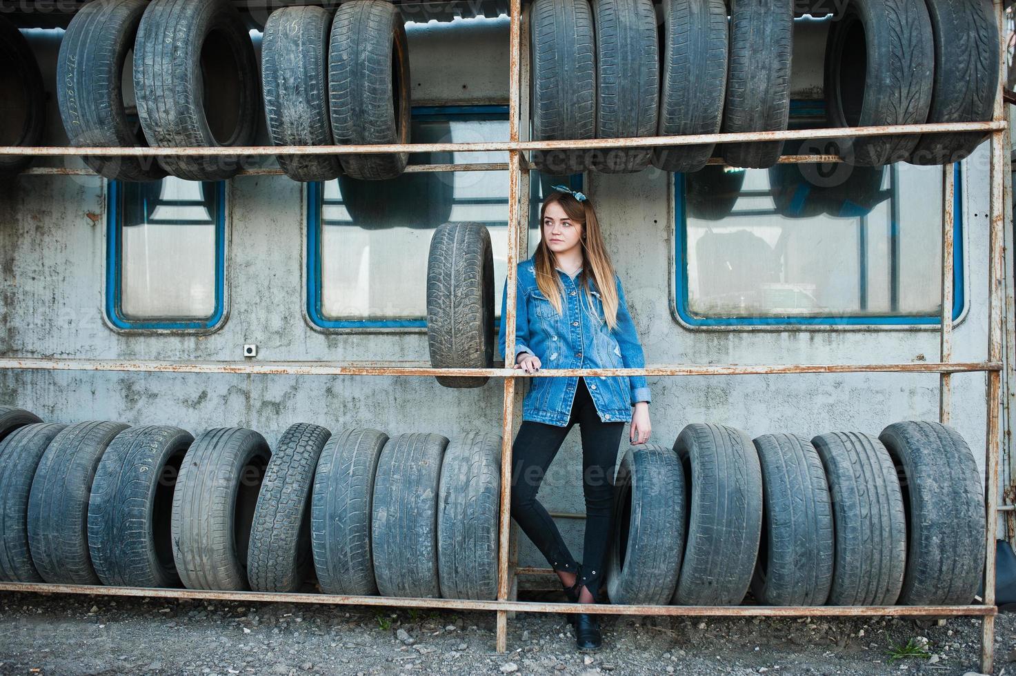 jeune fille hipster en veste jeans et foulard à la zone de montage des pneus. photo