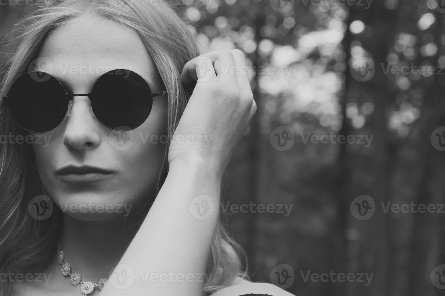 femme en lunettes de soleil rondes noires en noir et blanc photo