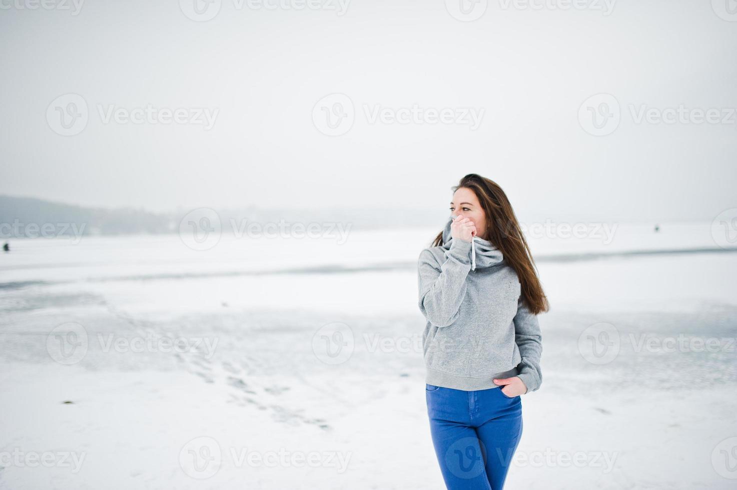 drôle de fille porter sur un pull à capuche et un jean, au lac gelé en hiver. photo