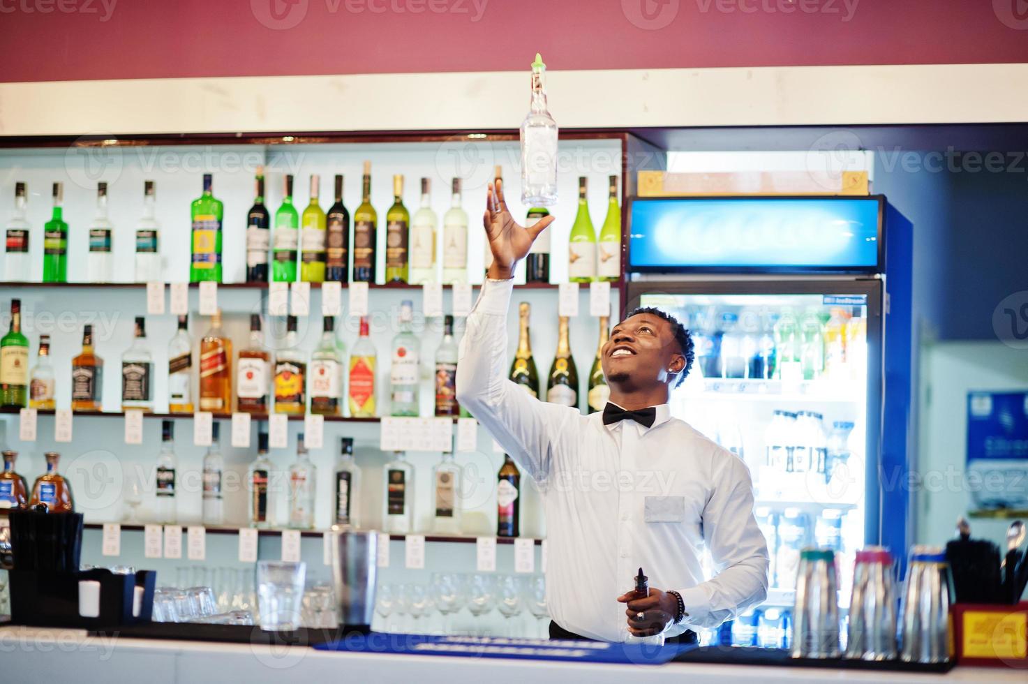 barman afro-américain au bar flair en action, travaillant derrière le bar à cocktails. préparation de boissons alcoolisées. photo