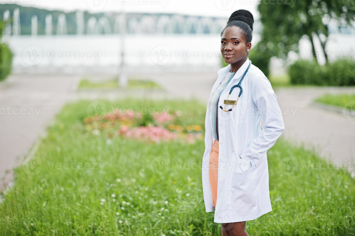 jeune femme médecin afro-américaine en blouse blanche avec un stéthoscope posé à l'extérieur. photo