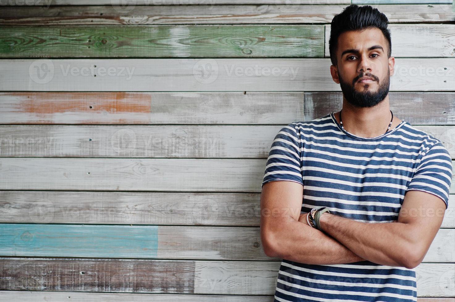 beau grand modèle d'homme à barbe arabe à chemise dépouillée posé en plein air sur fond de bois. mec arabe à la mode. photo