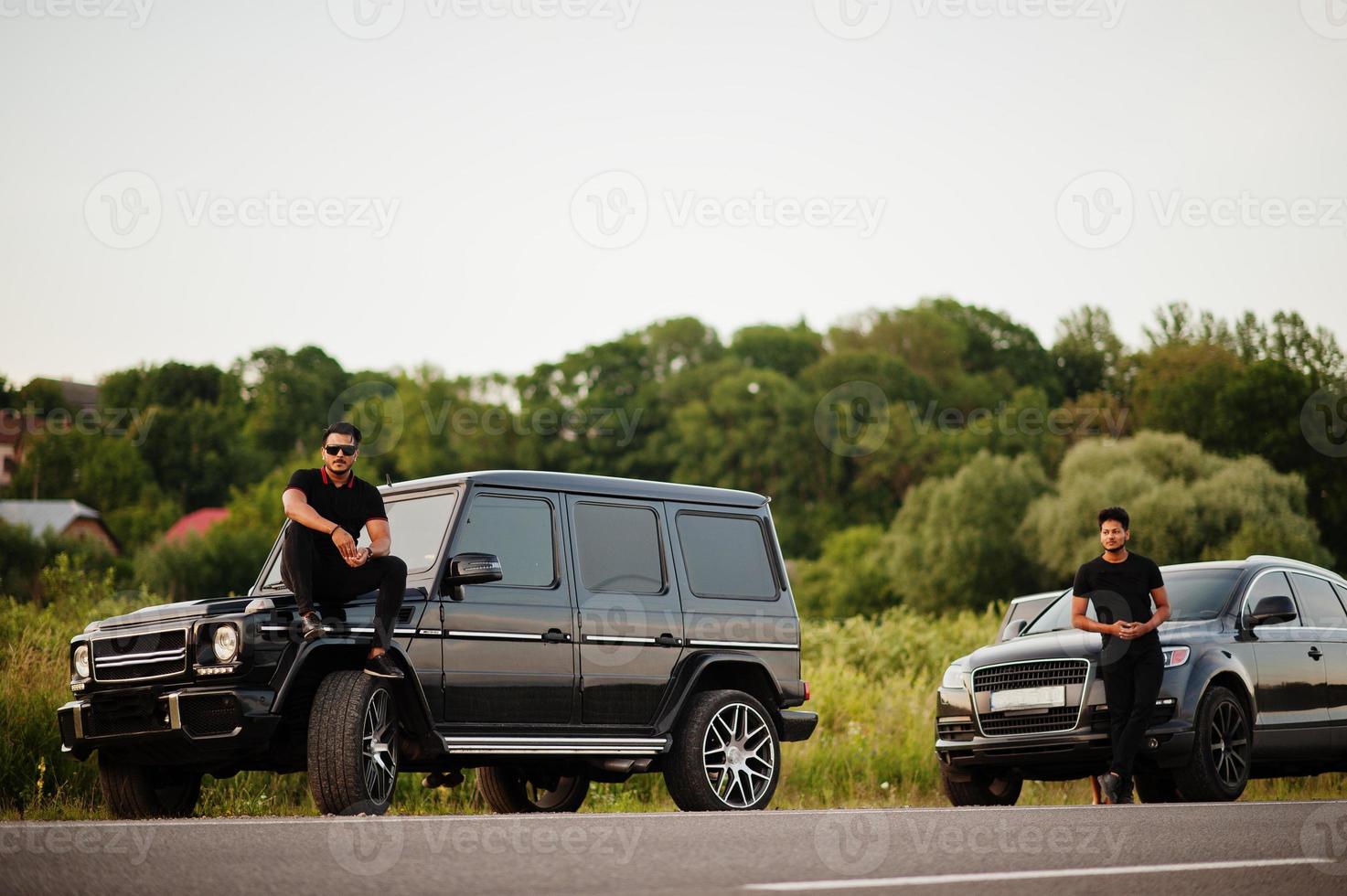 deux frères asiatiques portent un homme tout noir posé près de voitures suv. photo