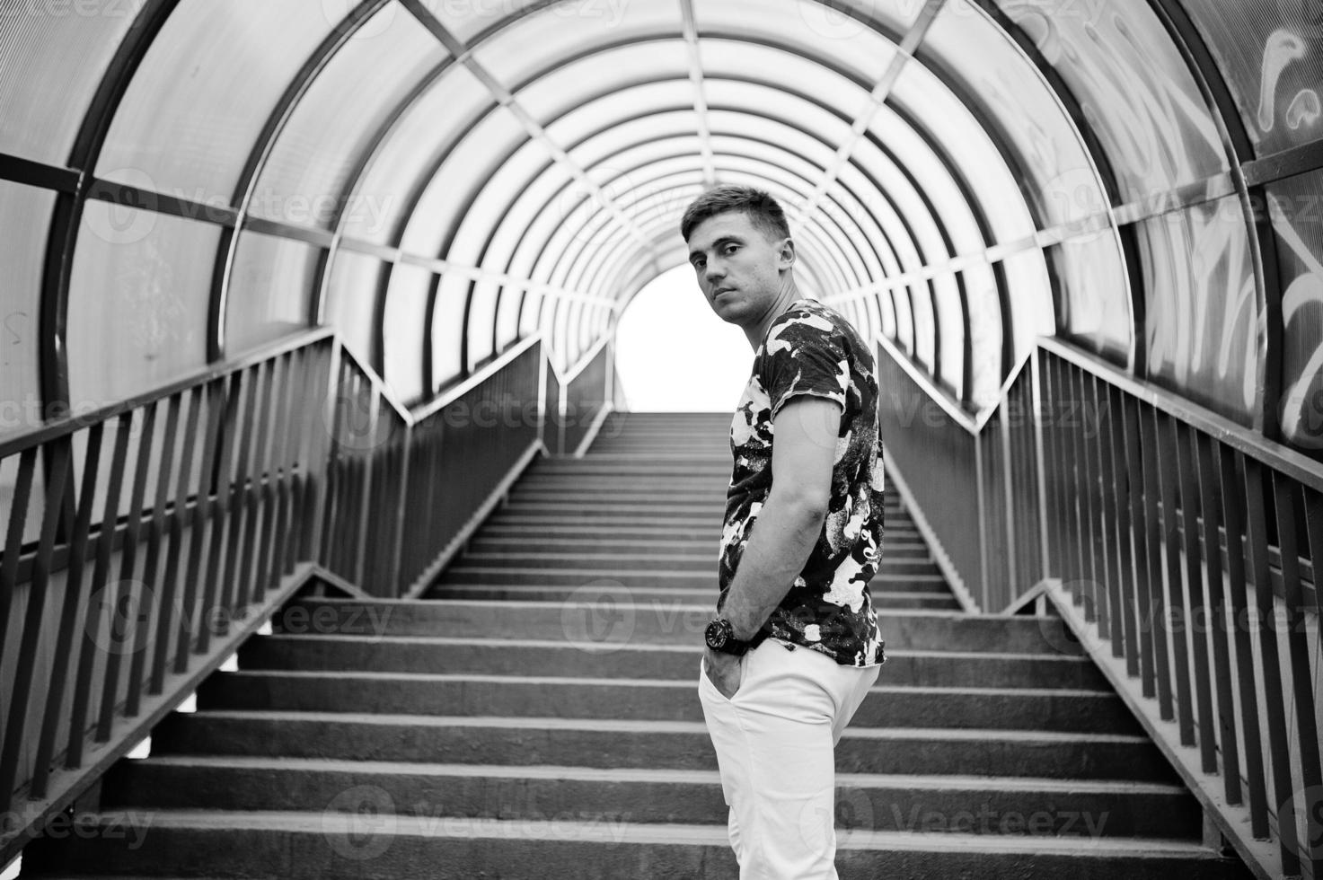 portrait de style de vie de bel homme posant dans les escaliers rouges du tonnel de la ville. photo