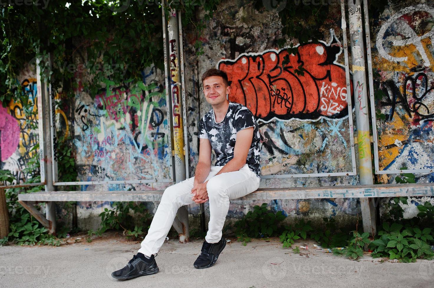 portrait de style de vie d'un bel homme posant dans la rue de la ville avec un mur de graffitis. photo