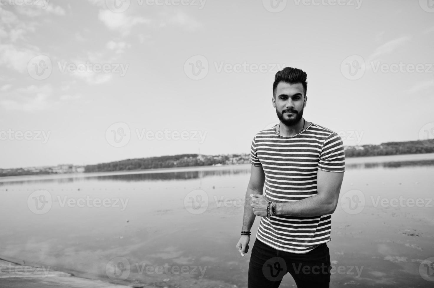 beau grand modèle d'homme à barbe arabe à chemise dépouillée posé à l'extérieur. mec arabe à la mode. photo