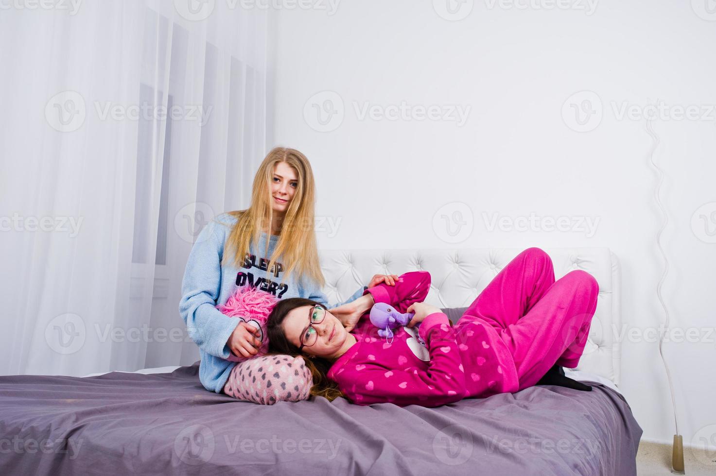 deux amis filles en pyjama s'amusant sur le lit dans la chambre. photo