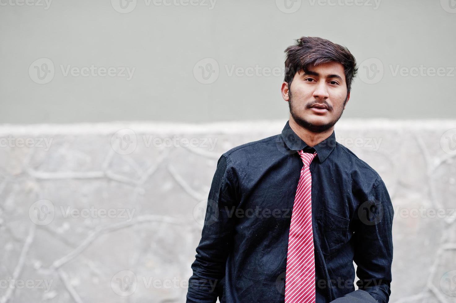 jeune homme indien sur chemise noire et cravate posée en plein air. photo