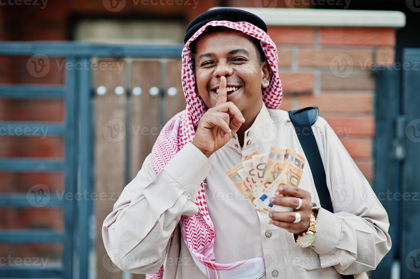 homme d'affaires arabe du moyen-orient posé dans la rue contre un bâtiment moderne avec sac à main noir et argent en euros. photo