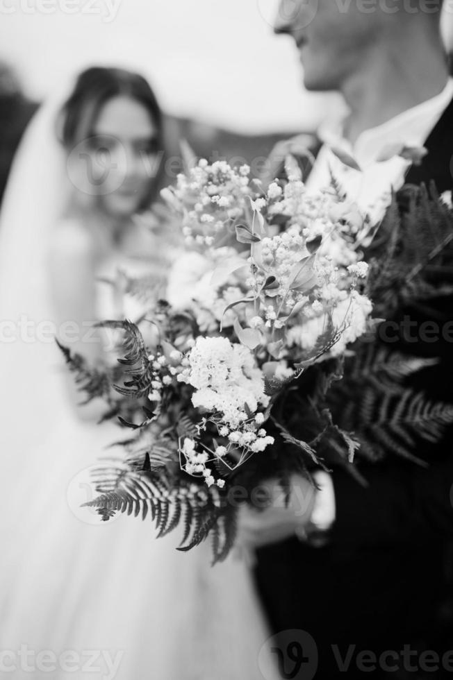 mariée et le marié tenant un beau bouquet de mariage tendre. photo