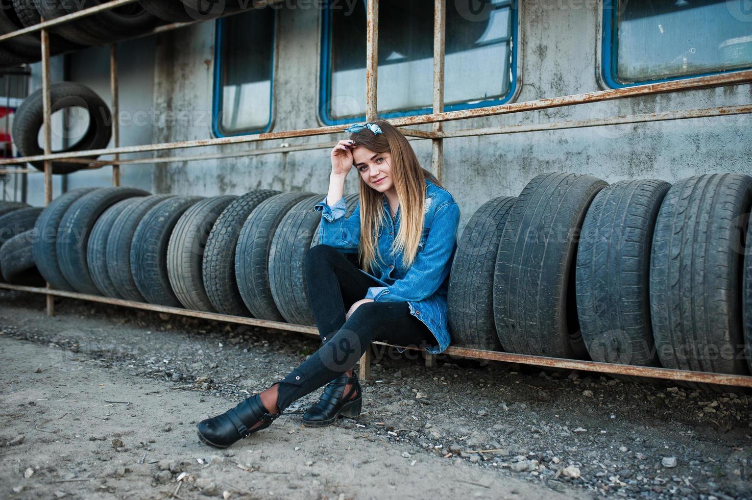 jeune fille hipster en veste jeans et foulard à la zone de montage des pneus. photo