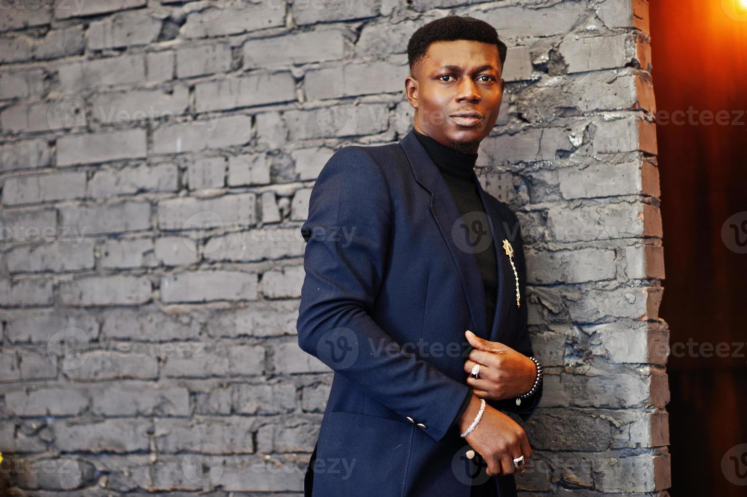 homme afro-américain à la mode en costume posé contre un mur de briques au café. photo