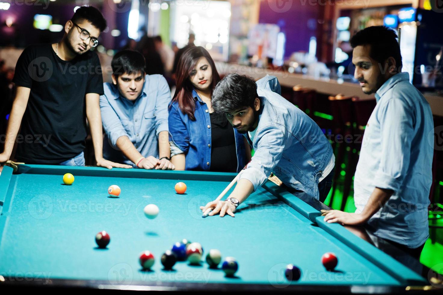 groupe d'amis asiatiques élégants portent des jeans jouant au billard au bar. photo