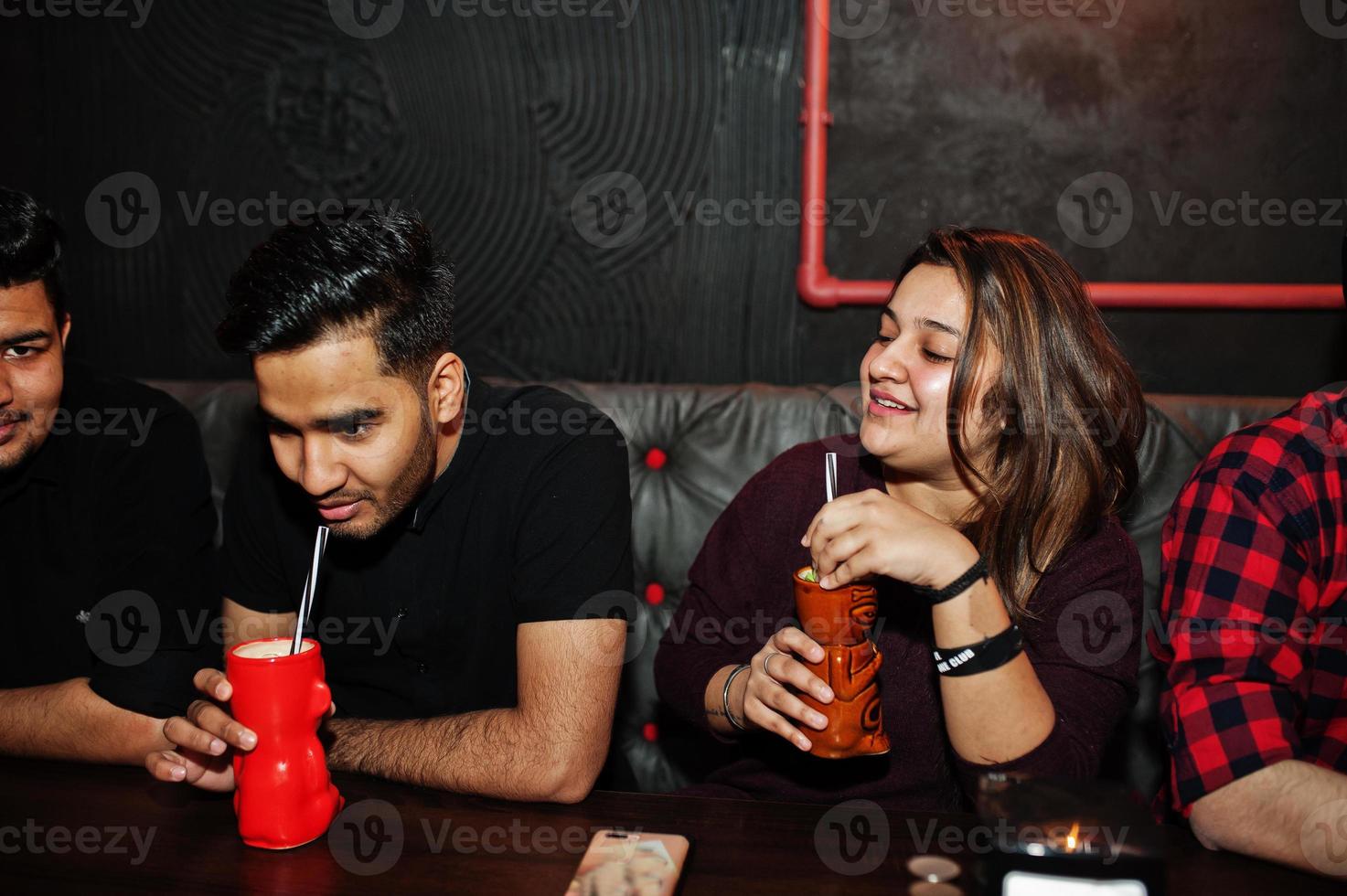 groupe d'amis indiens s'amusant et se reposant à la discothèque, buvant des cocktails. photo