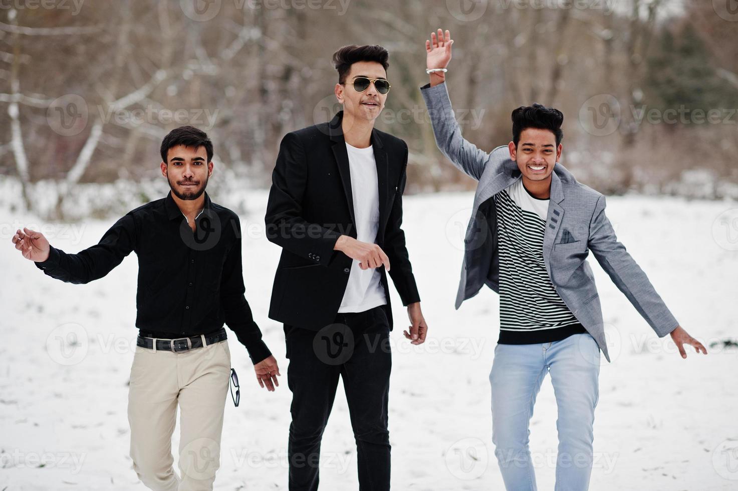 groupe de trois jeunes hommes indiens décontractés posés le jour de l'hiver s'amusant et dansant. photo