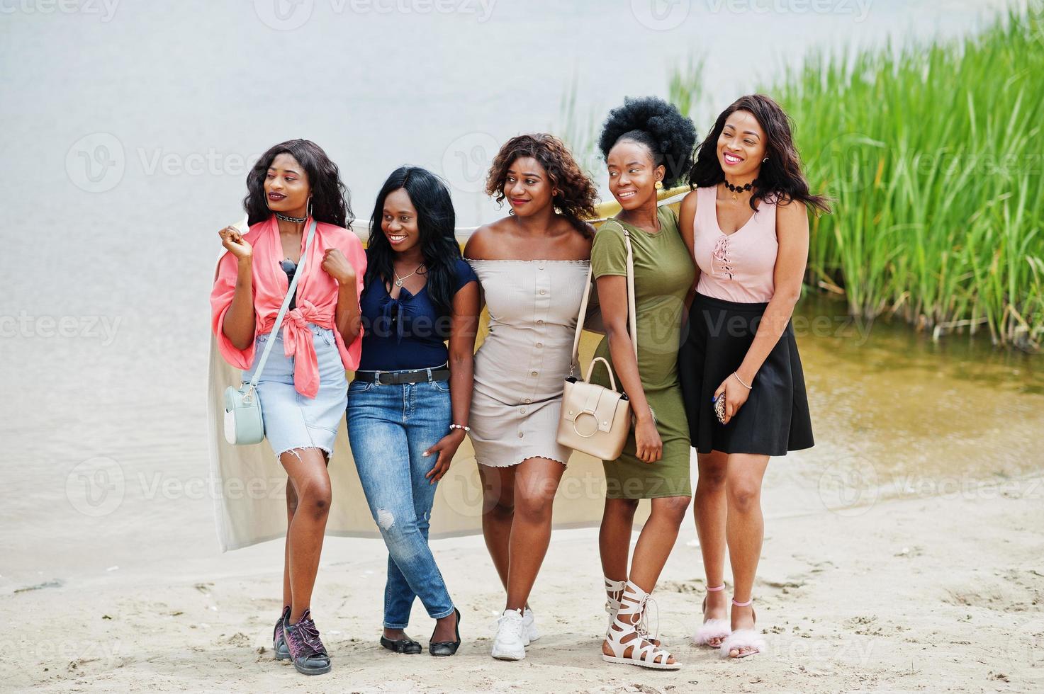 groupe de cinq filles afro-américaines debout au sable contre le lac. photo