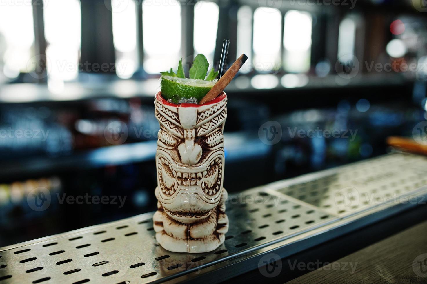 cocktail alcoolisé à la menthe et au citron vert dans un verre de terre vaudou à l'origine sur une table de bar. photo
