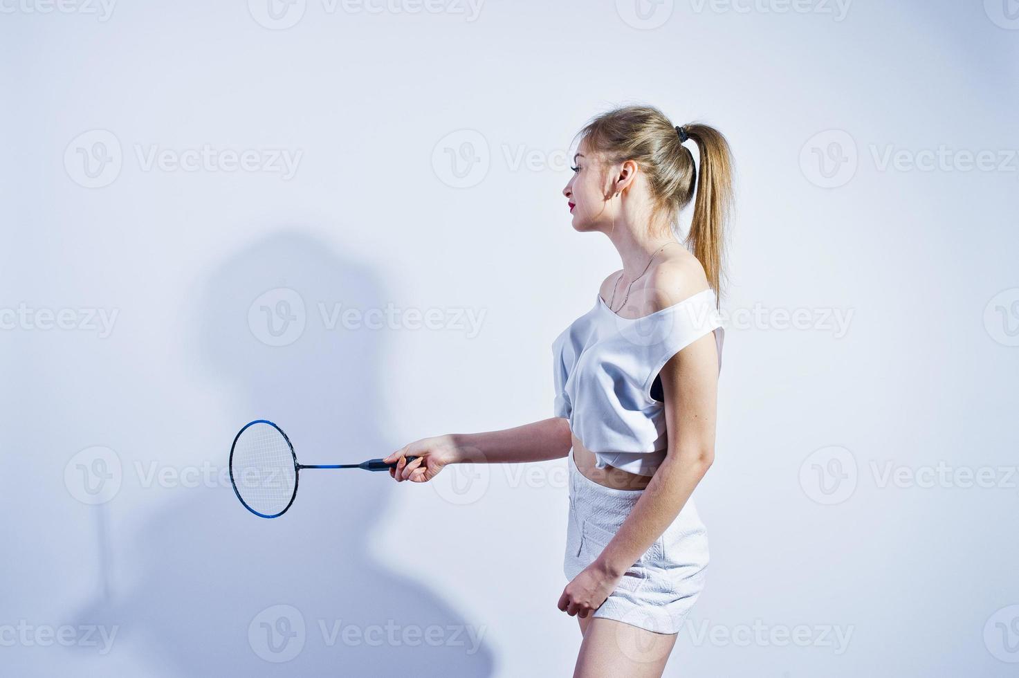 incroyable corps sexy brune caucasienne fille posant au studio sur fond blanc sur un short et un haut avec une raquette de badminton. photo