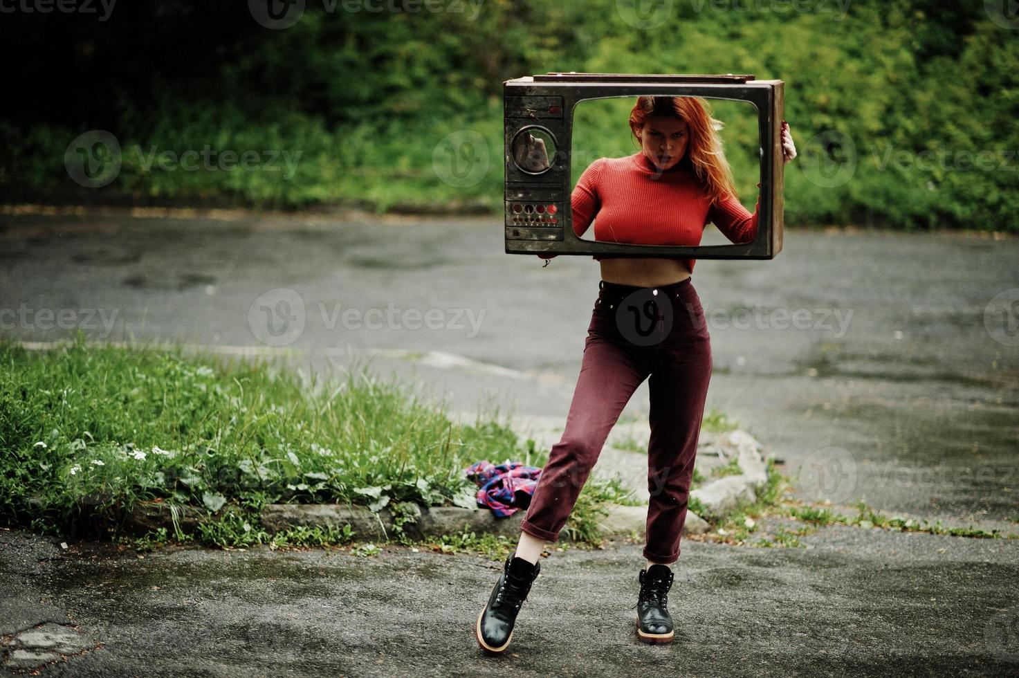 portrait de mode de fille sexy rousse en plein air. modèle séduisante femme dramatique avec une vieille boîte de télévision. photo