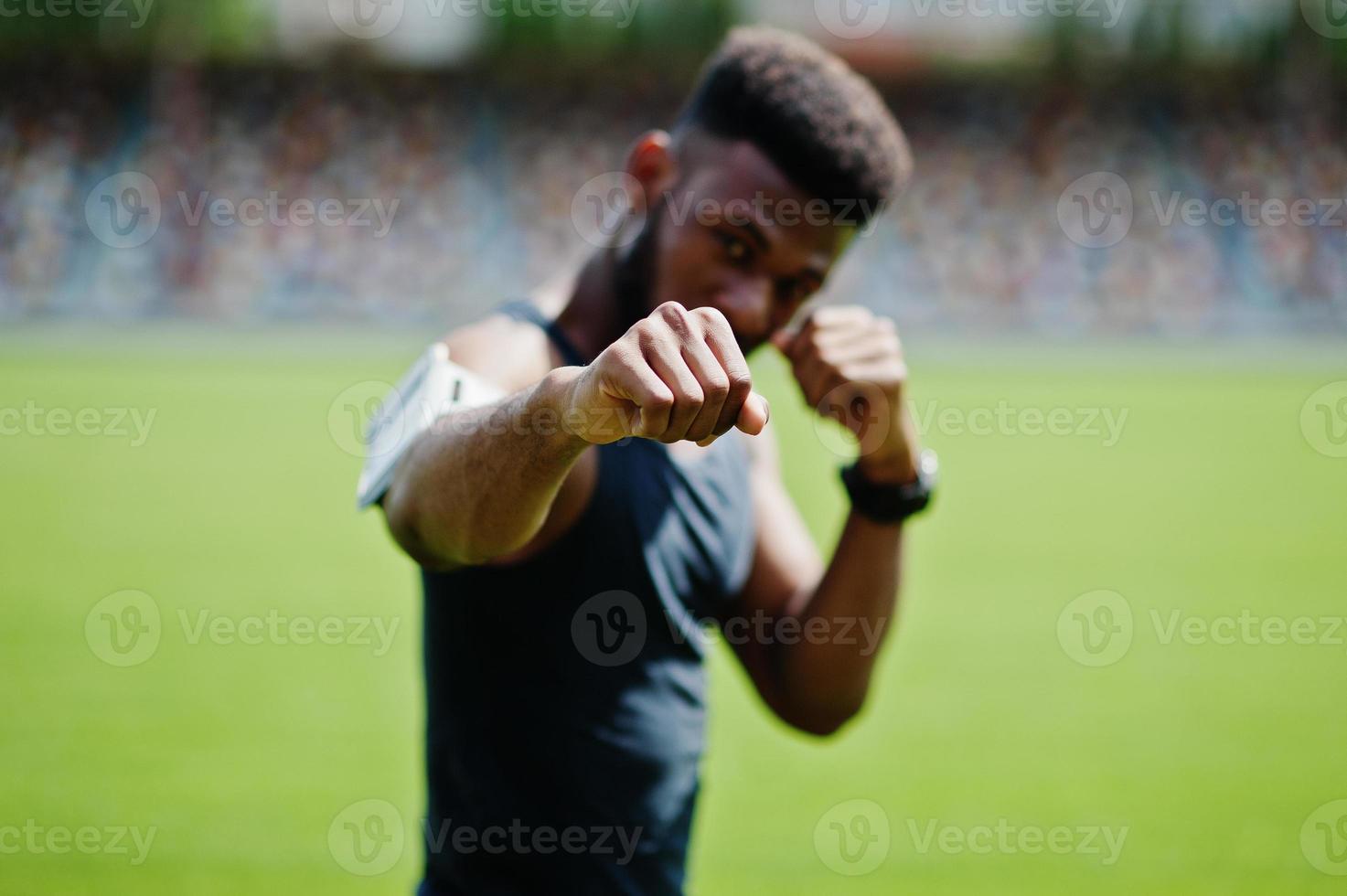 boxeur athlète masculin afro-américain en vêtements de sport faisant des étirements au stade. photo