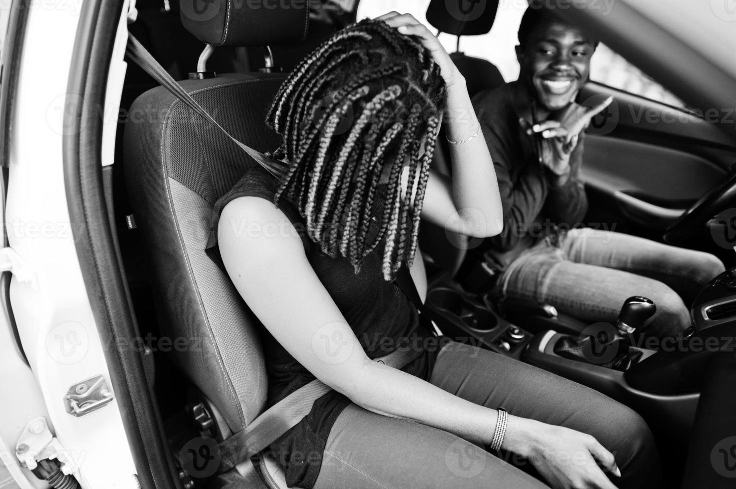 beau jeune couple afro-américain assis sur les sièges passagers avant tandis que bel homme conduisant une voiture. écouter de la musique et de la danse. photo