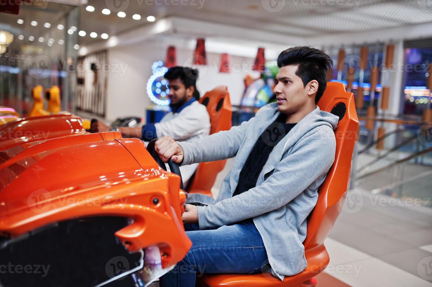 deux mecs asiatiques s'affrontent sur une machine de simulateur de course de jeu d'arcade speed rider. photo